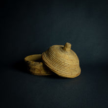 Load image into Gallery viewer, Handwoven African basket with a conical lid on a dark background.Handwoven African basket with a conical lid on a dark background.Handwoven African basket with a conical lid on a dark background.