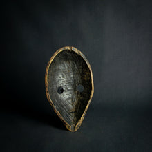 Load image into Gallery viewer, an mask from West Africa featuring round eyes and a serene expression, mounted on a stand against a dark background.