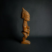 Load image into Gallery viewer, Hand-carved wooden statue of a mother holding a child, embodying fertility and continuity in African culture.