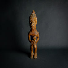 Load image into Gallery viewer, Hand-carved wooden statue of a mother holding a child, embodying fertility and continuity in African culture.