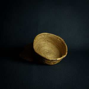 Handwoven African basket with a conical lid on a dark background.