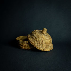 Handwoven African basket with a conical lid on a dark background.Handwoven African basket with a conical lid on a dark background.Handwoven African basket with a conical lid on a dark background.