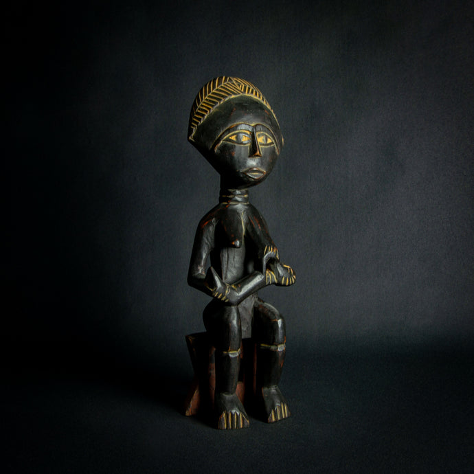 Intricately carved Ashanti Maternity figure, symbolizing fertility and traditional Ashanti motherhood, set against a dark backdrop.