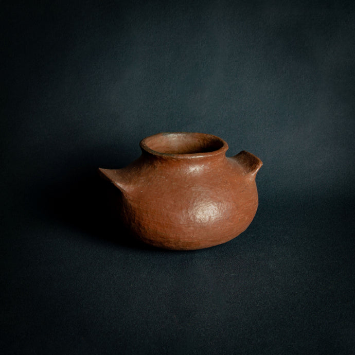 Vintage round terra cotta pot with handles on a dark background