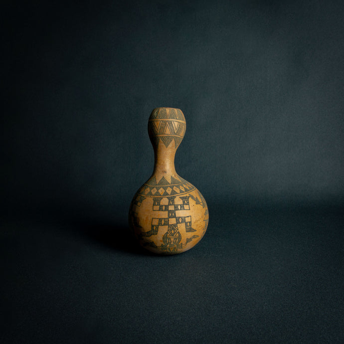 Intricately designed Dogon calabash, featuring traditional geometric patterns and cultural symbols, set against a dark background.