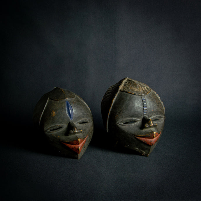 Vintage Dan tribal masks, one female and one male, showcasing the traditional craftsmanship of the Dan people from West Africa.