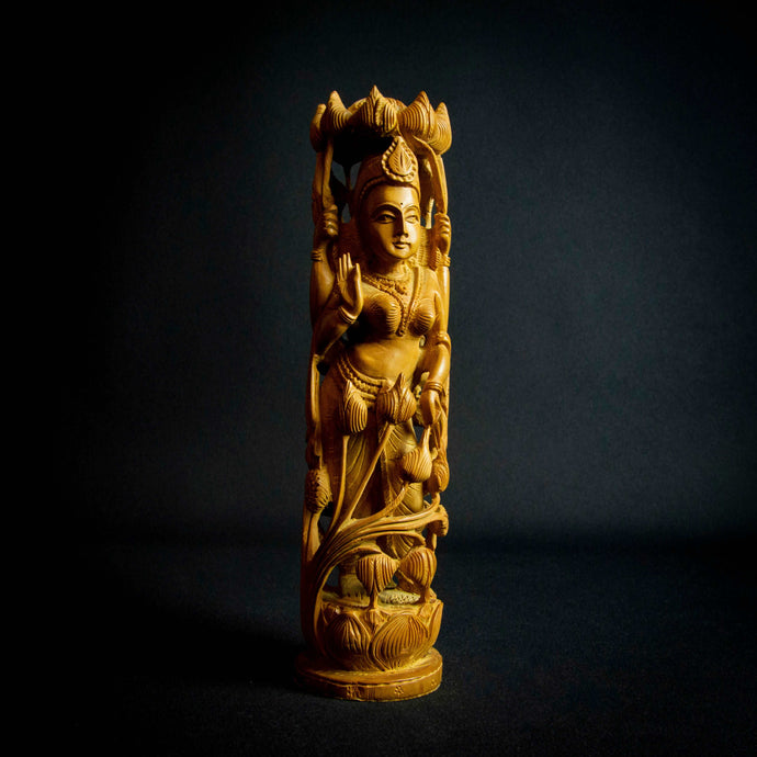 Hand-carved sandalwood statue of Hindu Goddess Lakshmi, adorned with lotus flowers.