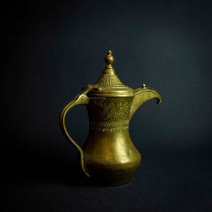 Antique Islamic teapot made of brass and copper with intricate designs and engravings on the exterior.