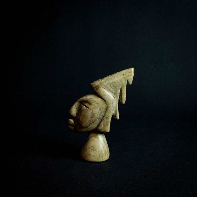 Stone sculpture of a male head with expressive features and a striking hairdo, likely from Zimbabwe.